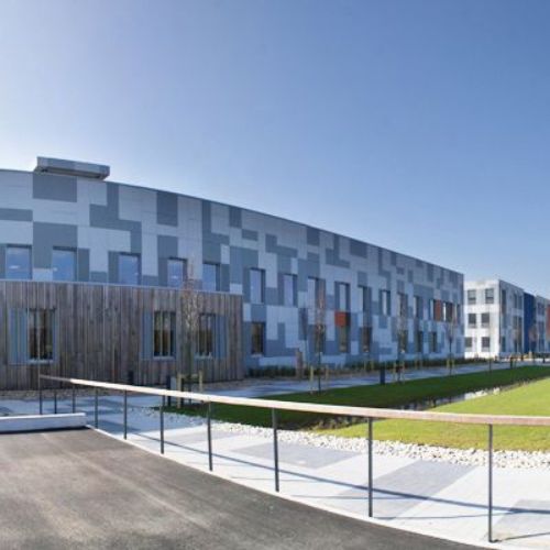 extérieur d'un batiment moderne avec ciel bleu et un carré d'herbe devant