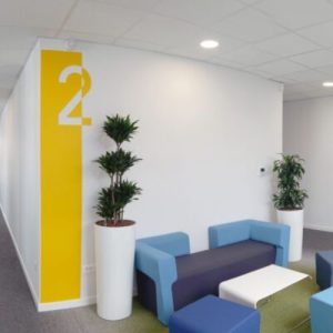 signaletique-kiloutou salle d'attente entreprise avec canapé et une signalétique jaune sur le mur